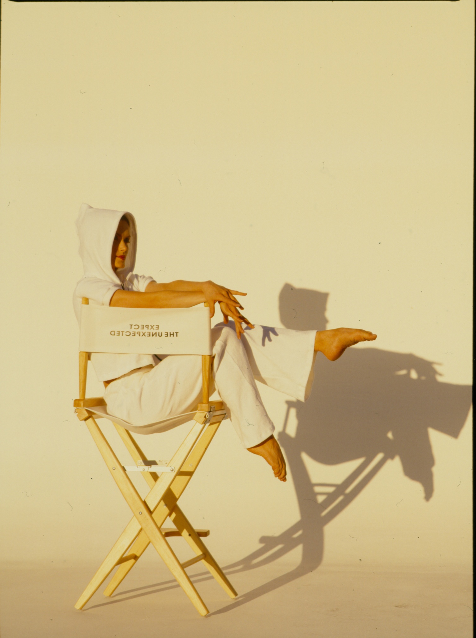 Model in a director's chair wearing Carushka's Spring/Summer 1995 collection, the original blueprint for modern athleisure, featuring the iconic tagline 'Expect the Unexpected'