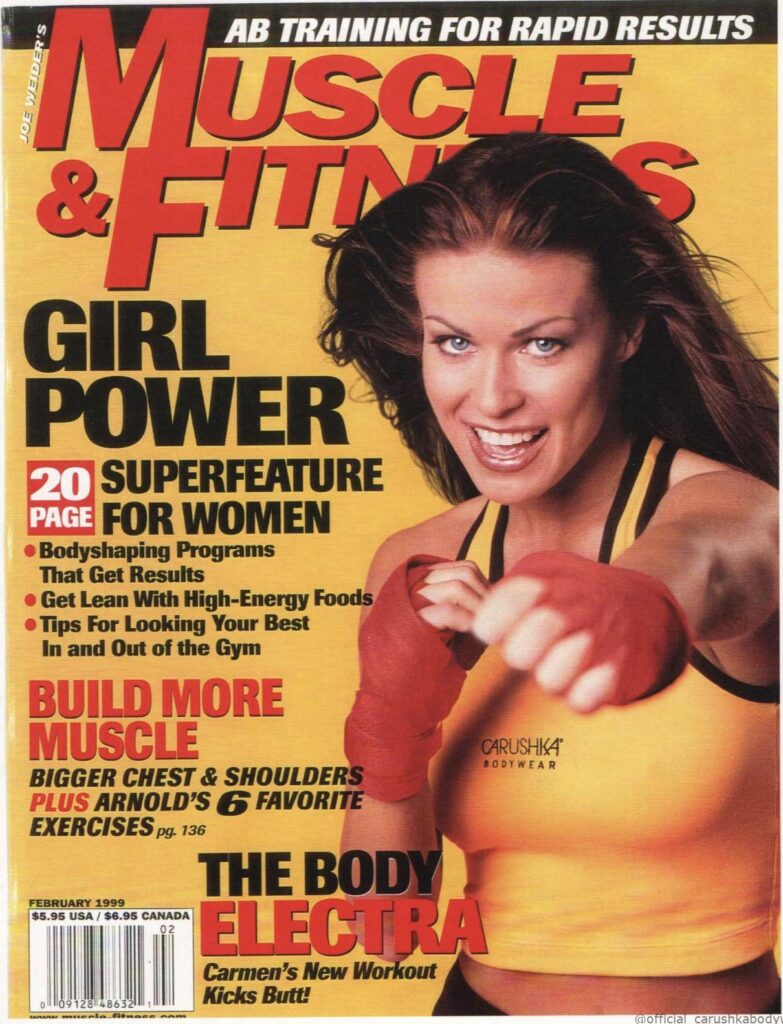 February 1999 cover of Muscle & Fitness magazine featuring pop-culture icon Carmen Electra. Titled "GIRL POWER," she is captured in a high-energy boxing pose wearing a yellow and black Carushka Bodywear crop tank top with the distinctive "CARUSHKA BODYWEAR" brand logo clearly stamped on the left side, celebrating late-90s athletic celebrity style.