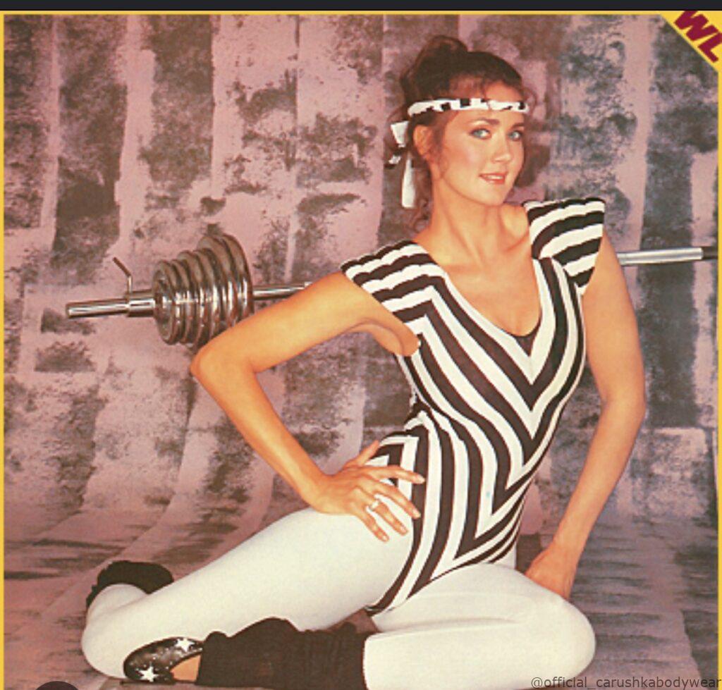 Lynda Carter posing for Shape Magazine’s 1st Anniversary issue (1982) wearing a signature Carushka Bodywear horizontal mitered-stripe leotard. The design features Carushka Jarecka's iconic architectural stripe alignment, defining the 1980s fitness aesthetic.