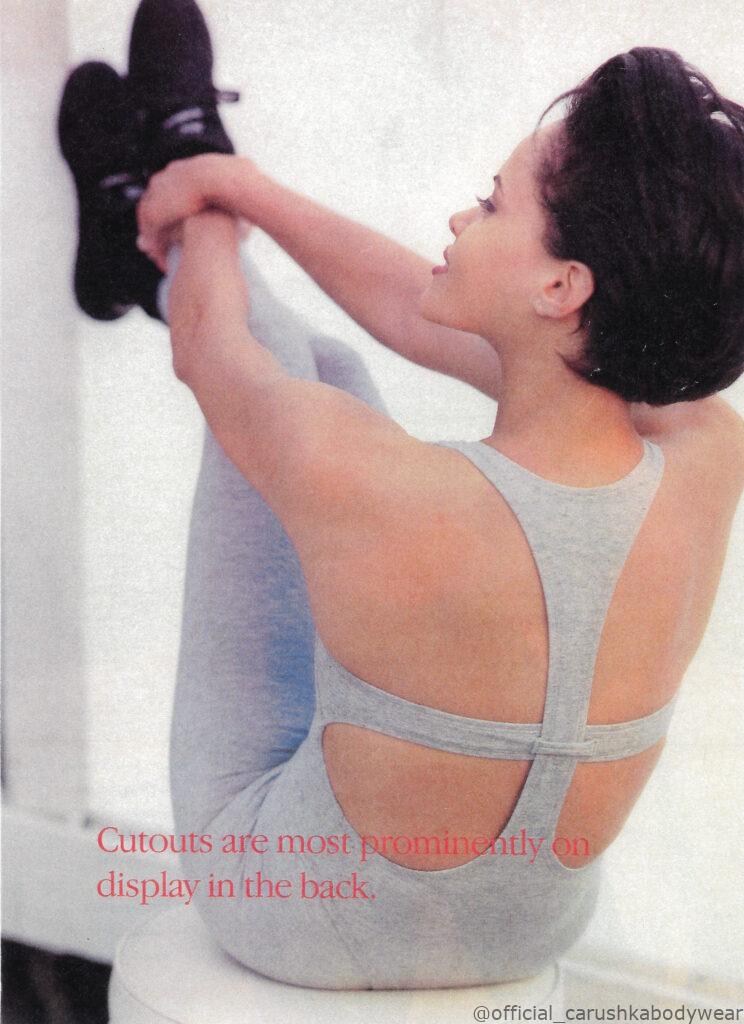 A 1993 fashion editorial feature showcasing Carushka Bodywear. The image features a side and back view of a model in a deep stretching pose, wearing the #101 Basic Racerback Thong Leotard in Heather Grey layered over matching Heather Grey ankle-length leggings. The overlay text reads, "Cutouts are most prominently on display in the back," highlighting the intricate, architectural back strap engineering and superior athletic cut of Carushka's proprietary luxury cotton/poly blend.