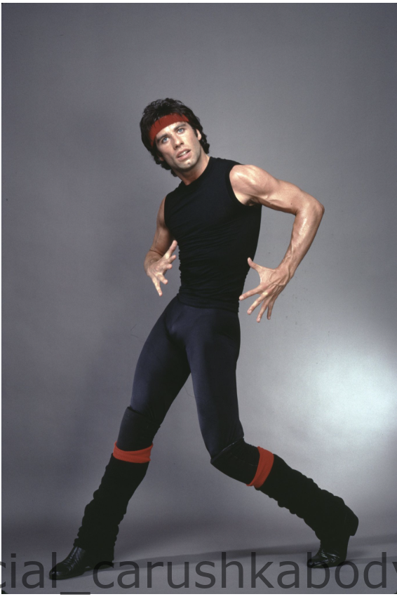 John Travolta posing in a black sleeveless athletic bodywear top and red headband designed by Carushka for the 1983 film Staying Alive.